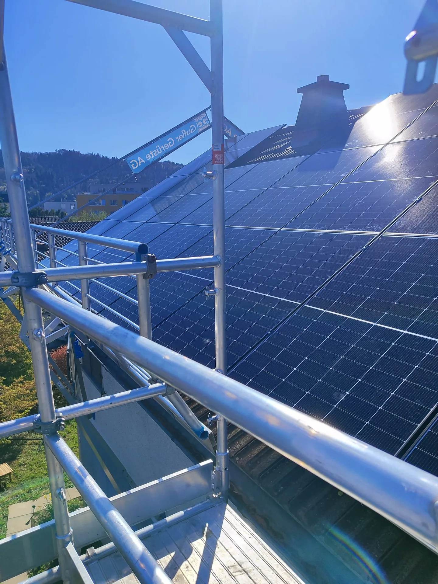 Photovoltaikmodule auf einem Schrägdach neben einem Baugerüst